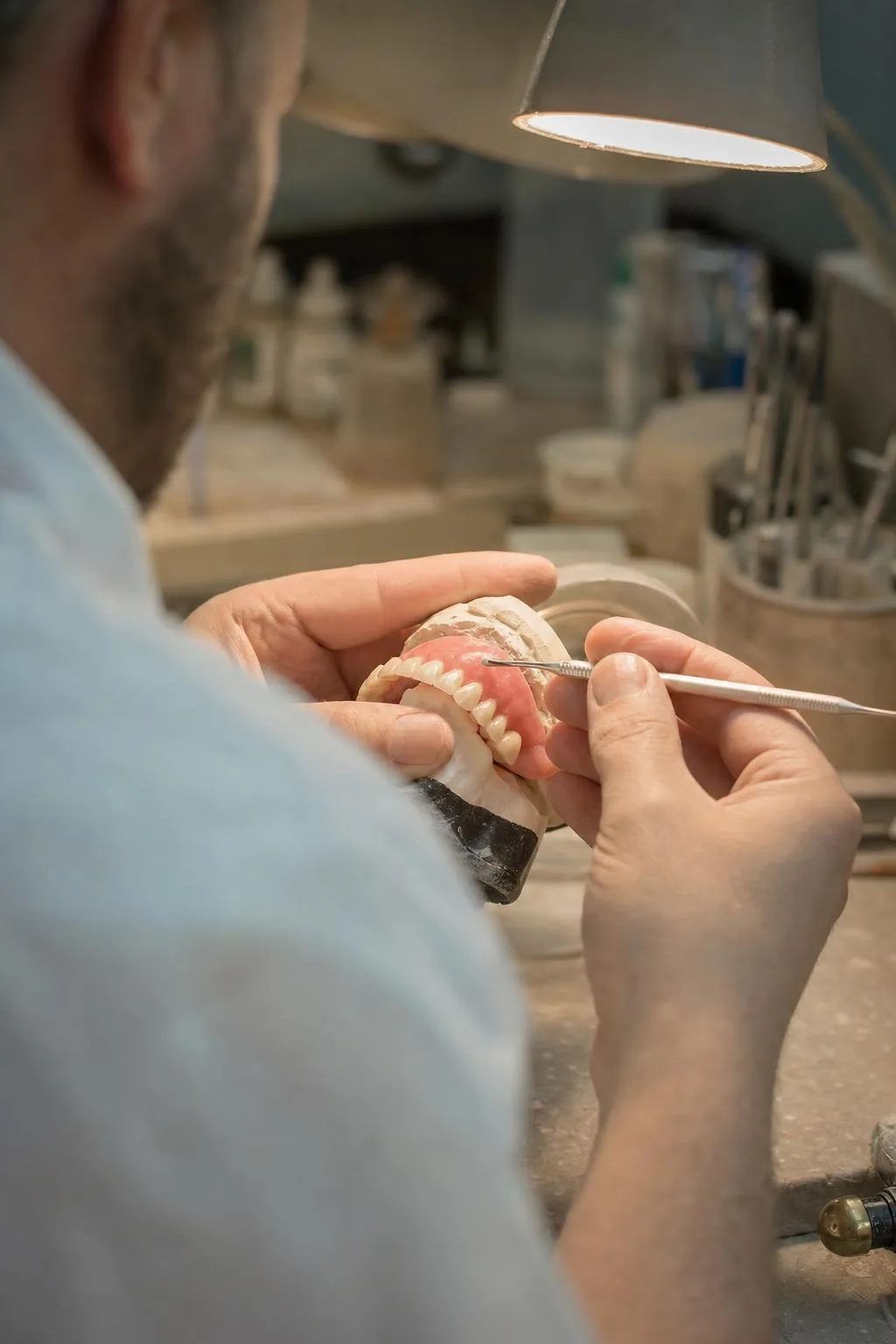 Dental technician shaping a denture set-up at the laboratory bench