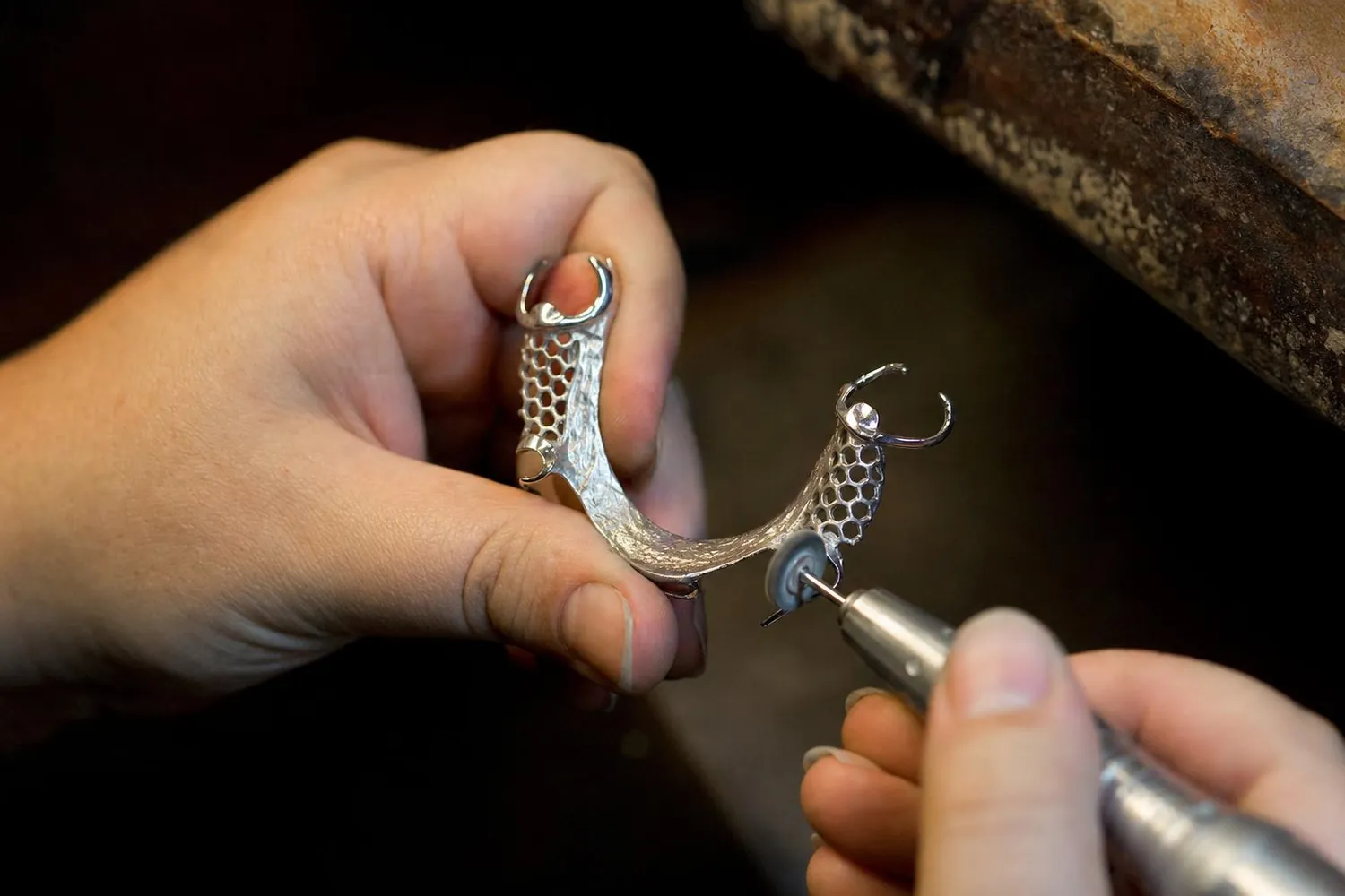 Dental technician polishing a chrome cobalt partial denture framework at the bench